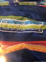 Close-up image of the Tommy Bahama logo on the fabric of the beach chair labeled 'Make Life One Long Weekend'
