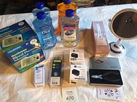 Photo of lot items including blood pressure monitor box, soaps, pulse oximeter box, pill splitter, toothbrushes, nail dryer, travel clippers, and mirror on table