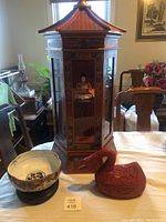 Overview of all four items: display case, doll inside, waterfowl container, ceramic bowl on stand