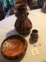 Wide shot of the three pottery items on table showing size relation and designs
