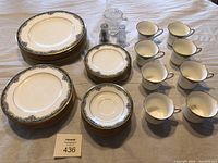 Full set of Noritake Mi Amor china displayed including plates, cups, saucers, creamer, and salt and pepper shakers on a table.