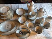 Overall arrangement of plates, bowls, cups, saucers, teapot, coffee server, sugar bowl, creamer, gravy boat, ladle, and serving platters