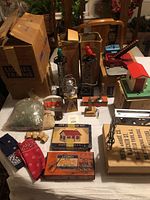 Photo showing the full lot of Lionel compatible vintage model train accessories arranged on a tabletop, including boxes and loose items such as signal towers, a coal loader, a red roof lamp house with crossing sign, and several small pieces and packs of wires.