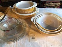 Overview of lot showing 2 yellow Butterprint oval casserole dishes with lids, 3 matching Cinderella mixing bowls, clear glass pie plate and measuring cup