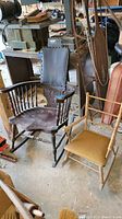 Two rocking chairs side by side in a garage: the antique adult rocker on the left, child's rocker on the right.
