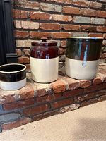 Three crocks lined up with two-tone glaze, showing size differences and colors
