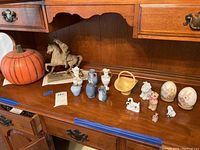 Wide view of all items on wood furniture including mini vases, metal horseback rider statue, and assorted figurines.