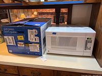 Microwave on counter next to original box and manual, showing full unit and packaging