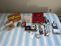 Full lot arranged on mattress showing jewelry pieces, watches, jewelry boxes, coins, and skeleton keys.