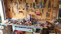 Overview of wooden workbench top with assorted hand tools scattered