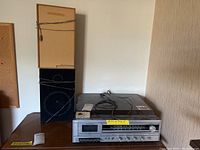 Full view of stereo system and two speakers placed on wooden furniture, showing overall condition and size.