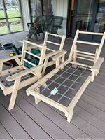 Wood chaise lounge and two wood armchairs with visible metal spring frames, no cushions shown, set on a porch deck.