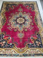 Full view of rug laid flat showing central medallion, field color and border design
