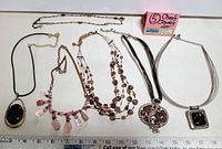 Photo of all six Chico's necklaces laid out with a ruler for length reference and a lot identifier label