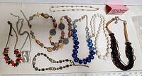 All 8 costume jewelry necklaces laid out side by side on a white background with measurement scale visible.