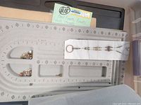 Gray felt bead board with assorted small metallic beads and a sample necklace placed on it