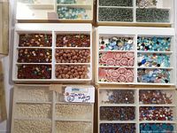 Lot overview showing multiple plastic trays arranged with diverse beads and jewelry making components.