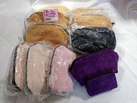 Full lot showing 10 leather clutches and coin purses in pink, gold, black, and purple arrayed on white background.