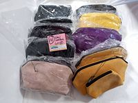 Lot of 10 new vintage leather handbags, clutches, and coin purses in various colors wrapped in plastic, displayed on white surface.