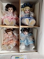 Four individually boxed porcelain dolls wrapped in bubble wrap, each doll visible from front view