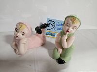 Photo of two vintage hand painted girl figurines, one pink reclining, one green sitting showing details and condition.