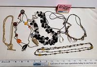 Full display of six vintage costume jewelry necklaces laid flat with a ruler for size reference.