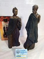 Photo showing two Maasai sculptures side by side with box in background and auction catalog card below.