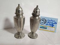 Two vintage VM Co Brooklyn 104 pewter salt and pepper shakers side by side on a white background.