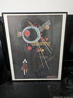 Photo of a 16x20 framed abstract art print with geometric lines and circles on a dark background.