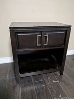 Front view of dark wood end table showing two-door cabinet and open shelf underneath.
