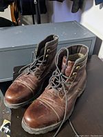 Photo of pair of brown leather lace-up men's boots with padded collar and rubber sole, showing front and top view.