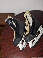 Pair of men's hockey skates on wooden table, showing inner and outer sides