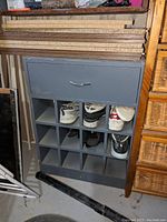 Shoe cabinet with 10 cubby compartments holding shoes and a closed top drawer