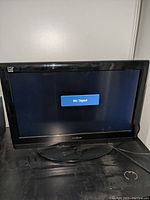 Front view of black Insignia TV showing a 'No Signal' message on screen, sitting on oval pedestal stand.