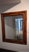 Full view of the rectangular wall mirror showing bamboo-style wooden frame and reflection.