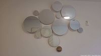 Full front view of the assembled cluster of 15 circular mirrors on a wall, showing their varying sizes and layout.