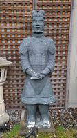 Front view of tall Chinese composite army statue showing detailed armor and signs of chipping damage.