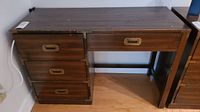 Full view of Kroehler wood desk showing three drawers on the left and one center drawer with brass handles, wood finish with surface wear.