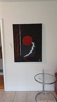 Full view of signed abstract canvas painting on a white wall, showing its size in relation to nearby furniture.