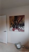 Wall-mounted square abstract painting showing mixed earthy tones and textured paint details in a room setting.