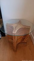 Three-quarter view of round glass top and bamboo base against wall