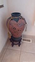 Full view of the ornamental pottery vase on the wooden stand, showing overall size and shape.