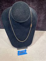 Full view of gold chain necklace draped on black display bust