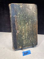 Closed view of the scrapbook showing the aged black cover with wear and damage.