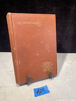 Front cover of Les Miserables book with brown cloth and gold embossed lettering.
