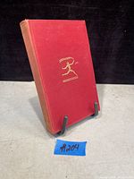 Front cover of the book showing red cloth binding with gold embossed figure and spine text.