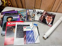 Vintage People magazines, sheet music books, calendars, yearbook, and rolled posters displayed on a flat surface