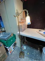Full-height view of brass-tone bridge floor lamp showing ornate base and curved arm with shade