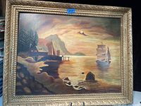 Frontal photo of the antique oil painting showing the ship, dock, houses, mountain, and gilded frame.