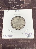 Front side of the 1910 Canadian 25 cents silver coin in holder, showing date and denomination with leaf wreath design.